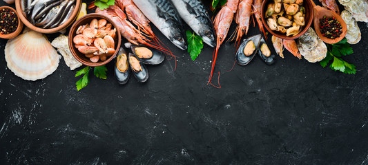 Fresh seafood on a stone background. Fish, shrimp, mussels, caviar. Top view. Free copy space.