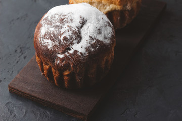 Homemade muffins with sugar powder on the dark, textured background