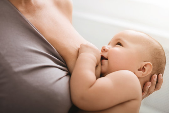 Smiling baby looking in mother's eyes, during breast feeding