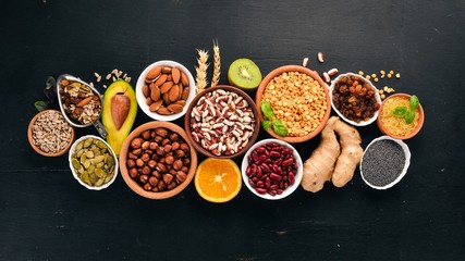 Obraz na płótnie Canvas Various superfoods. Dried fruits, nuts, beans, fruits and vegetables. On a black wooden background. Top view. Free copy space.