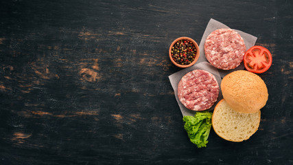 Raw burger Cooking a burger with meat. On a black wooden background. Top view. Free copy space.