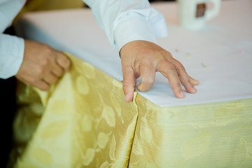Hands of staff preparing the tablecloth with pin and decorations