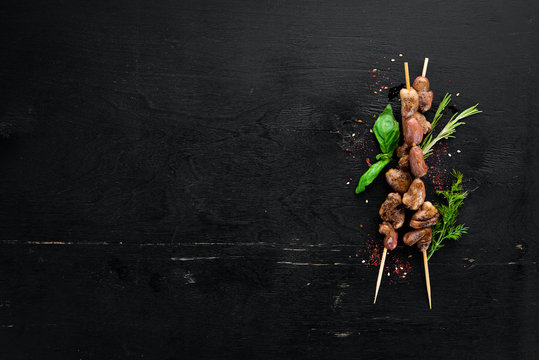 Skewers of chicken heart. On a wooden background. Top view. Free space for your text.