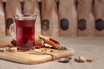 Glass of hot tea and wooden spoon with dried tea leaves.