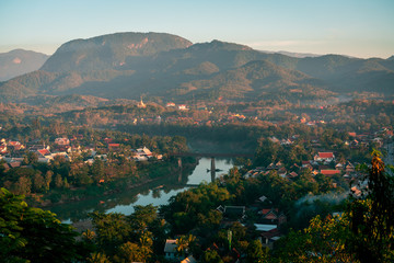 Sunset in Lunag Prabang, Laos. Beautiful clouds over the city. Mekong river between trees and houses. Winter in Laos