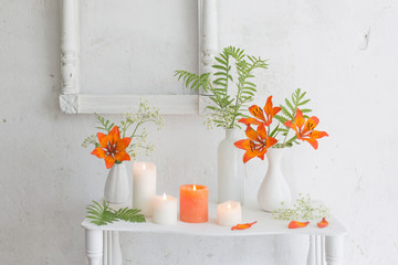 forange flowers and candles on white background