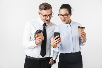 Colleagues couple isolated over white wall background drinking coffee using mobile phones.