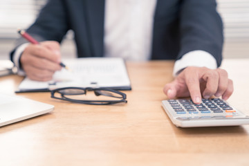 Fototapeta premium Start up business man or accountant checking his business graph working on laptop computer and calculator on office table.