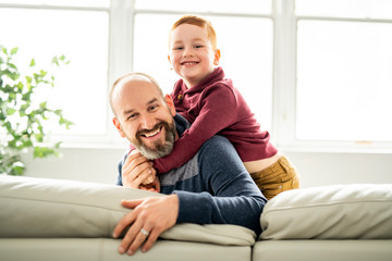 Father with redhead child sit on the sofa at home