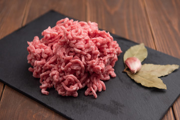 Fresh minced pork on black plate and wooden background.