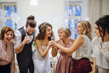 A young bride with other guests dancing and singing on a wedding reception.