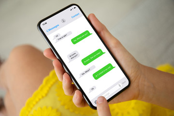 female hands in yellow dress holding phone with app messenger
