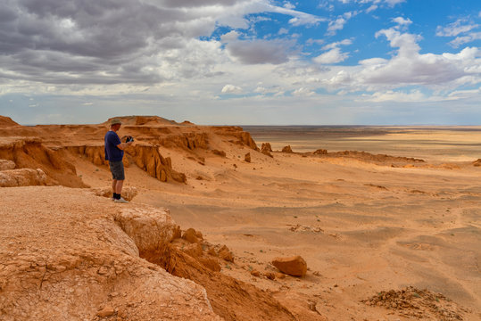 Man standing in desert taking a photo, Flaming Cliffs, Gobi Desert, Bulgan, Mongolia