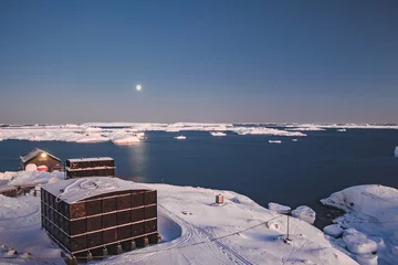 Rolgordijnen Antarctisch onderzoek Vernadsky stationsgebouwen naast de kustlijn van Antarctica. Schitterend winterlandschap. Het besneeuwde land omringd door de bevroren oceaan. De barre omgeving. Nacht scene © Goinyk