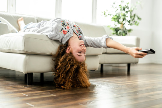Positive redhead teenage girl lying on a couch.
