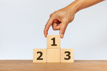 Hand arranging wooden cube with the number 1 2 3 on white background. Concept of success, winner, victory or top ranking