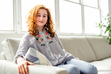 Obraz premium Positive redhead teenage girl lying on a couch.