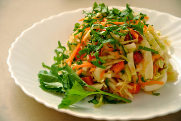 Beautiful colorful salad of fresh vegetables and parsley on a white plate on the table.