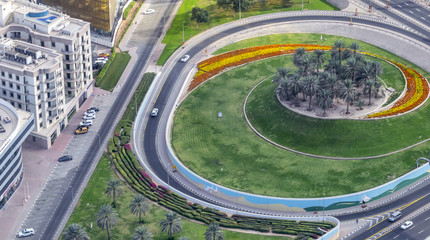 Big roundabout with flowers and grass along main highway, aerial view