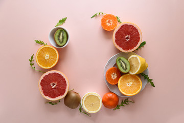 Tropical fruits frame from orange, lemon, tangerine and kiwi on pink paper background. Healthy food concept. flat lay. Top view