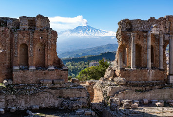 Volcano Etna seen through ruins of ancient Greek amphitheater in Taormina in Sicily