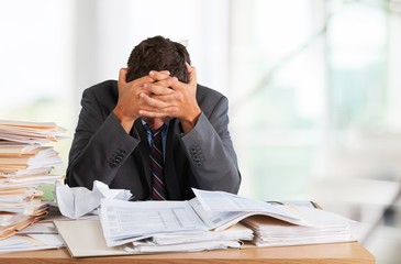 Tired young businessman with stack of papers