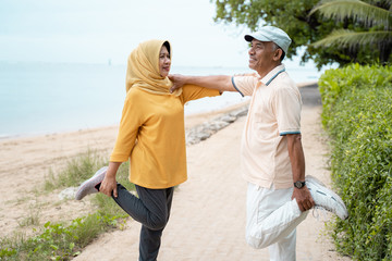 senior man and woman support each other while stretching 