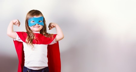 Portrait of  beautiful little girl in superhero costume on sky