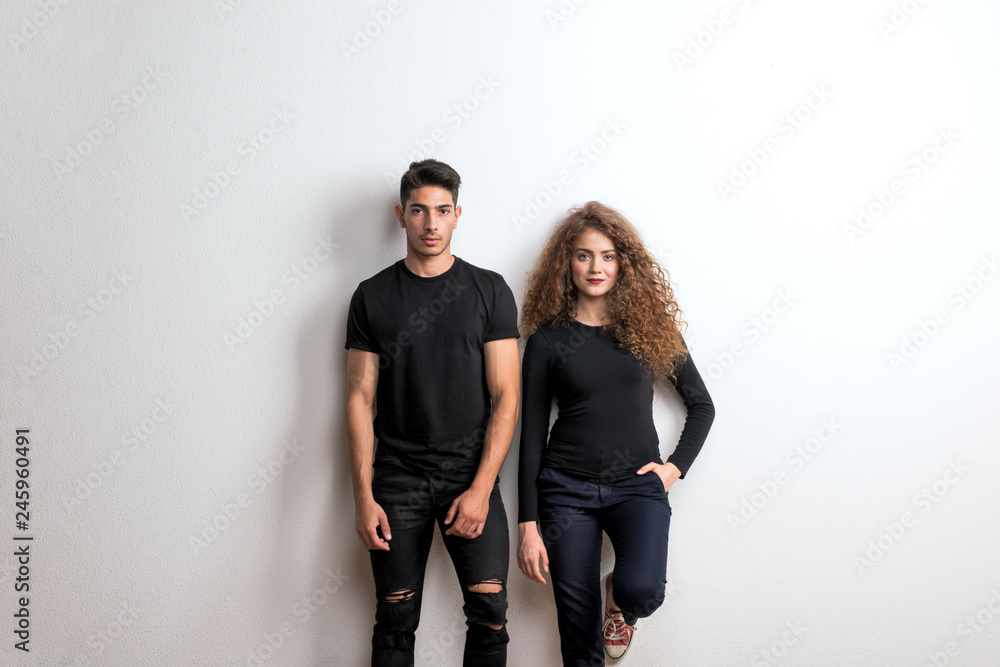 Wall mural portrait of a young couple standing in a studio, wearing black clothes.