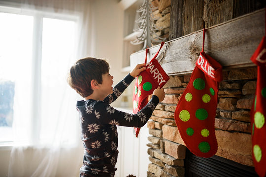 Smiling boy hanging a Christmas stocking on a fireplace