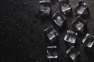 Pieces of ice cubes with water droops on black background.