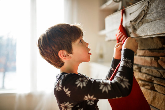 Boy hanging a Christmas stocking on a fireplace