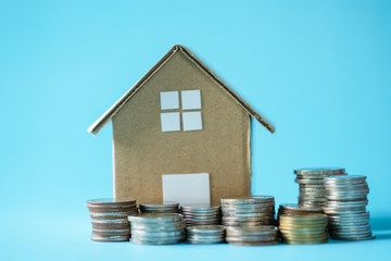 House model around with stacking coins money on blue background. Saving and investment to real estate concept. -image.