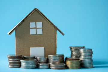 House model around with stacking coins money on blue background. Saving and investment to real estate concept. -image.