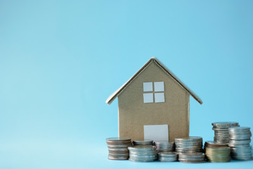 House model around with stacking coins money on blue background. Saving and investment to real estate concept. -image.