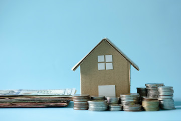 House model around with stacking coins money on blue background. Saving and investment to real estate concept. -image.