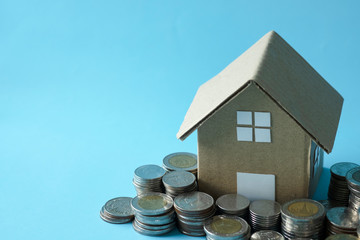 House model around with stacking coins money on blue background. Saving and investment to real estate concept. -image.