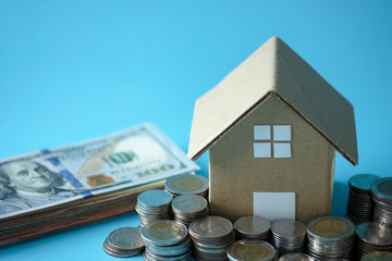 House model around with stacking coins money and banknote on blue background. Saving and investment to real estate concept. -image.