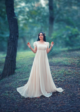 Mysterious lady in a white vintage dress, lost in the woods. Black long hair is decorated with a golden laurel wreath, like that of the Greek Goddess. Creative, artistic colors