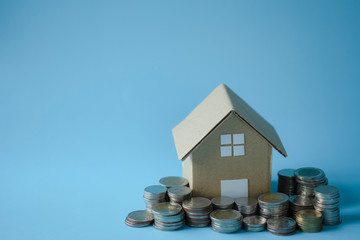 House model around with stacking coins money on blue background. Saving and investment to real estate concept. -image.