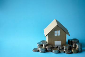 House model around with stacking coins money on blue background. Saving and investment to real estate concept. -image.