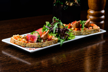 Delicious dish. Fresh bread with juicy meat slices served with caviar, strawberries and lettuce in white plate