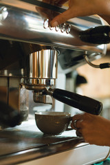 Cropped picture of female hands of bartender cooking coffee latte in a hipster modern coffee shop using coffee machine and equipment