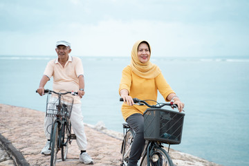 happy senior muslim couple exercising riding bicycle together 