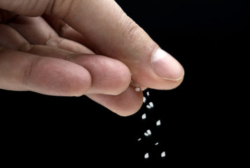 Hands spreading salt on black background