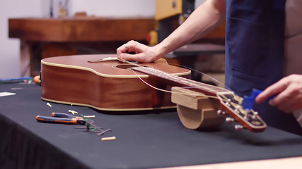 Luthier repairs guitar, changes strings