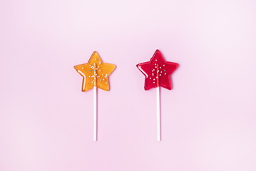 Yellow and Red Stars Shaped Lollipop on Light Pink Background Homemade Fruit Lollipop Candy Background Flat Lay Top View Copy Space