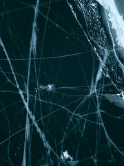 View of the frozen Lake Baikal in winter from drone. Ice cracks on lake. Slippy, cracked and cold frozen ground of Baikal, Irkutsk, Siberia, Russia.