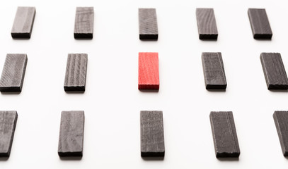 Red wooden block between black ones on white