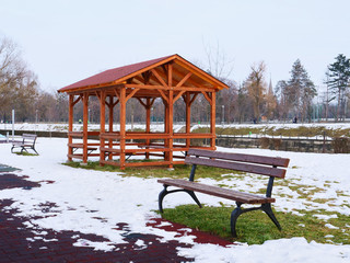 Wooden pavilion and empty bench in the snow covered landscape